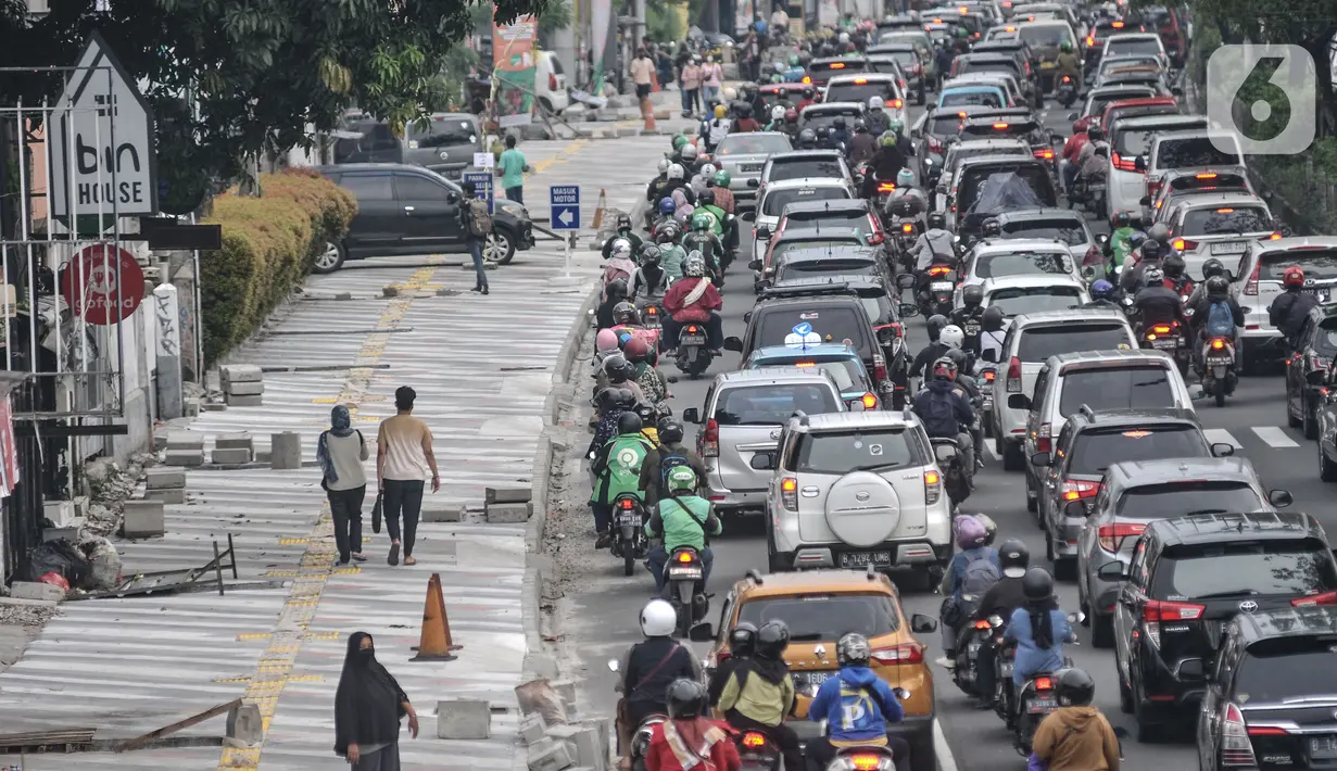 Pejalan kaki saat melintasi trotoar yang tengah direvitalisasi di Jalan Margonda Raya, Depok, Jawa Barat, Minggu (4/12/2022). Pemerintah Kota Depok lewat Dinas Pekerjaan Umum dan Penataan Ruang (DPUPR) menganggarkan Rp23,5 miliar untuk revitalisasi trotoar di Jalan Margonda. (merdeka.com/Iqbal S Nugroho)