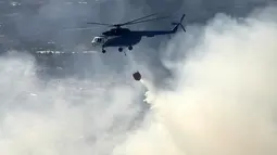 Sebuah helikopter menjatuhkan air untuk memadamkan kebakaran hutan di Bukit San Marcos, wilayah munisipalitas Villa de Leyva, Departemen Boyacá, Kolombia, pada 20 September 2026.(LUIS LIZARAZO / AFP)