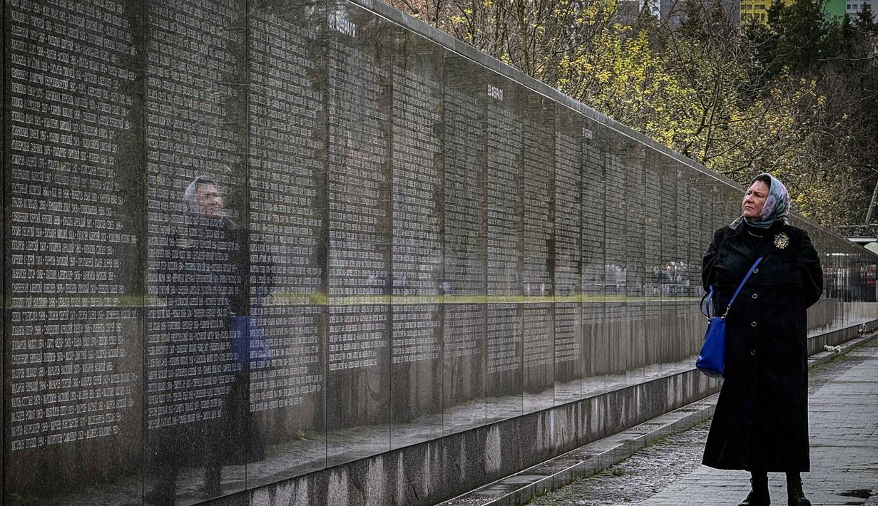 Seorang perempuan mengunjungi tugu peringatan bagi para korban represi politik di Butovo, di luar Moskow, pada Kamis 30 Oktober 2025, menandai hari peringatan. Keberadaan lapangan tembak Butovo sebagai tempat eksekusi sempat dirahasiakan selama puluhan tahun. (Nikita BORISSOV/AFP)