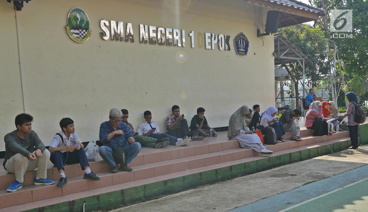 Siswa dan orangtua murid menunggu saat mengikuti seleksi Penerimaan Peserta Didik Baru (PPDB) di SMAN 1 Depok, Kota Depok, Jawa Barat, Selasa (18/6/2019). Sistem PPDB Jawa Barat berlangsung pada tanggal 17-22 Juni 2019. (Liputan6.com/Herman Zakharia)