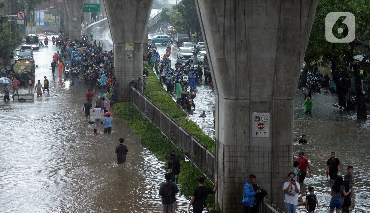 Warga menyusuri Jalan Kapten Tendean yang terendam banjir, Jakarta, Sabtu (20/2/2021). Banjir yang disebabkan curah hujan tinggi memutus akses lalu lintas di Jalan Kapten Tendean. (merdeka.com/Imam Buhori)