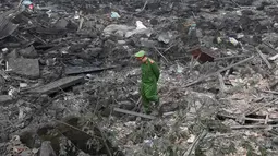 Seorang polisi berjalan melintasi puing-puing setelah sebuah ledakan besar menghancurkan lima rumah dan bangunan di sekitar provinsi utara Bac Ninh (3/1). Ledakan tersebut juga melukai enam orang lainnya. (AFP Photo/Hoang Dinh Nam)