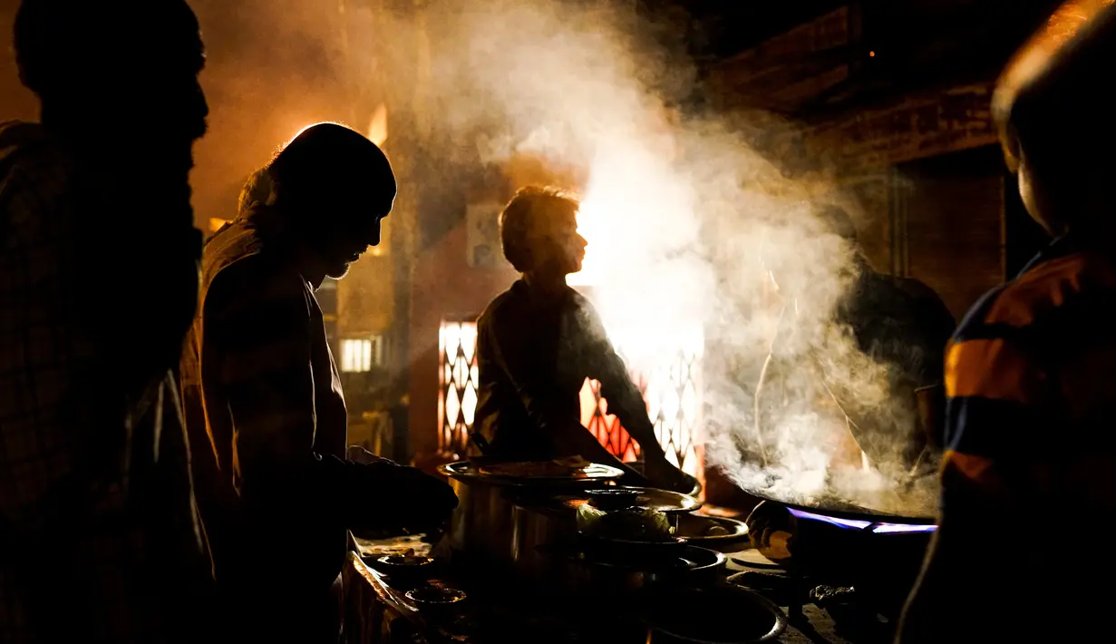 Sejumlah buruh makan malam di sebuah warung makanan pinggir jalan di kawasan tua New Delhi, India (6/3). Sebelumnya India sempat menjadi negara dengan pertumbuhan ekonomi paling pesat di dunia. (AFP Photo/Chandan Khanna)