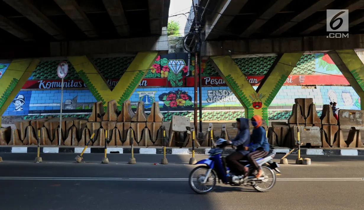 Seniman dari Komunitas mural dan Gravity menyelesaikan gambar di Kolong Tol, Jakarta, Rabu (19/6/2019). Pembuatan Mural Gravity tersebut bermaksud untuk membuat lingkungan sekitar menjadi indah dan elok dipandang mata. (Liputan6.com/Johan Tallo)
