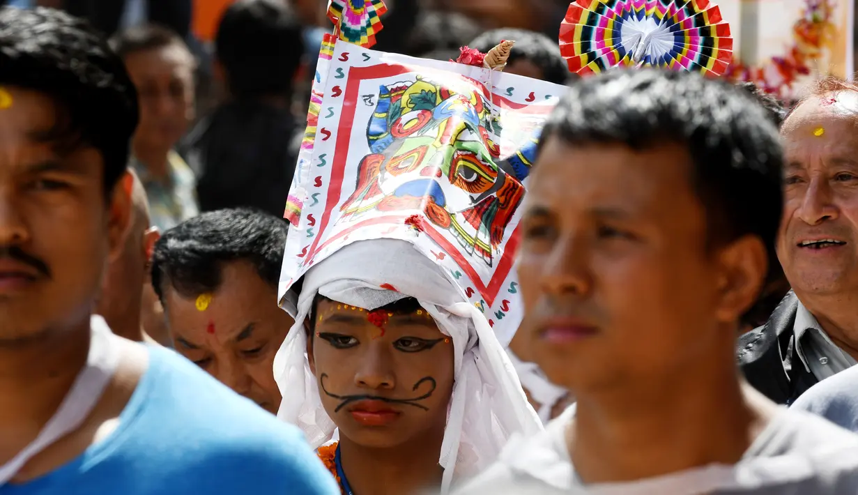 Ekspresi seorang anak Nepal yang mengenakan kostum saat mengikuti Gai Jatra cow festival di Kathmandu, Nepal (8/8). Festival ini digelar untuk meminta keselamatan dan kedamaian. (AFP Photo/Prakash Mathema)