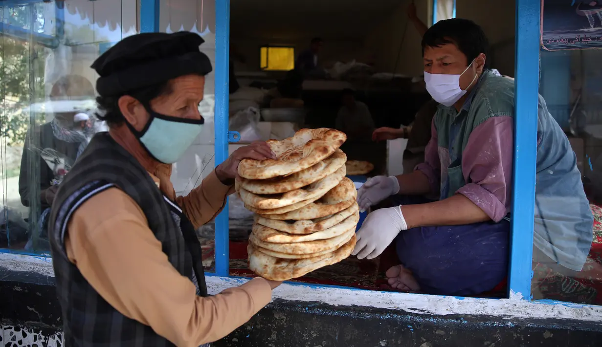 Seorang pria menerima roti gratis dari kota selama lockdownuntuk mencegah penyebaran virus corona, pada bulan puasa suci Ramadan di Kabul, Afghanistan, Senin, (4/5/2020). Muslim di seluruh dunia sedang melaksanakan Ramadan, ketika mereka menahan diri dari makan, minum dari subuh hingga senja. (AP/Ra