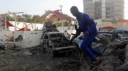 Tentara berjaga di sekitar bangunan yang hancur menyusul serangan bom mobil kembar di Ibu Kota Mogadishu, Somalia, Sabtu (24/2). Ledakan kedua terjadi di dekat Istana Presiden Somalia. (AP Photo/Farah Abdi Warsameh)