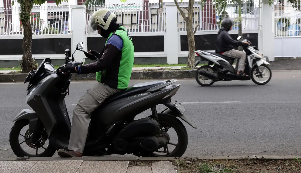 Pengemudi ojek online melihat telepon genggam di Kawasan Jalan Siliwangi, Kota Tasikmalaya, Jawa Barat, Sabtu (3/9/2022). Pemerintah resmi menaikkan harga BBM Bersubsidi pada Sabtu (3/9) pukul 14.30 WIB, sementara tarif ojek online (ojol) baru yang tertuang di Keputusan Menteri Perhubungan (KM) No.564/2022 kembali ditunda penerapannya seperti yang diumumkan pada Senin (29/8/2022). (Liputan6.com/Helmi Fithriansyah)