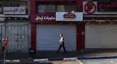 Seorang pria berjalan melewati toko-toko yang tutup selama pemogokan umum di Ramallah, sebelah barat laut kota itu di Tepi Barat, pada 11 Juni 2024. (Zain JAAFAR/AFP)