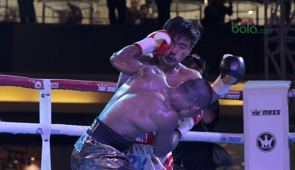 Pukulan Jansen Marapu mendarat di wajah petinju Thailand, Phuttiphong Rakoon saat tampil pada kelas Lightweight Mahkota Boxing Super Series di Cilandak Town Square, Jakarta (10/3/2018). Jansen menang TKO pada ronde ke sembilan. (Bola.com/Nick Hanoatubun)