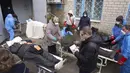 Jenazah disiapkan sebelum dimasukkan ke dalam kantong jenazah dan dimakamkan pada kuburan massal di pinggiran Mariupol, Ukraina, 9 Maret 2022. (AP Photo/Evgeniy Maloletka)