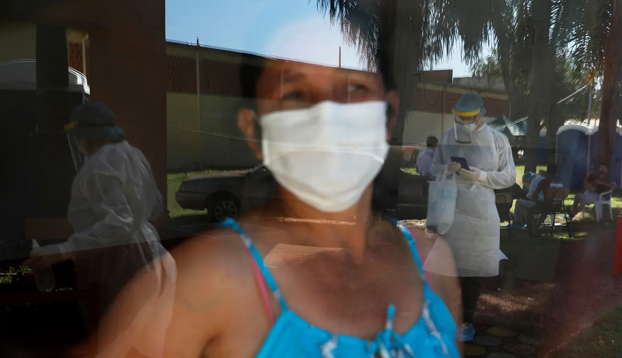 Seorang wanita yang menjalani karantina melihat melalui jendela sebuah sekolah di Ciudad del Este, Paraguay, Rabu (24/6/2020). Otoritas Paraguay mewajibkan warga yang kembali ke rumah dikarantina selama dua minggu untuk melewati dua tes COVID-19. (AP Photo/Jorge Saenz)