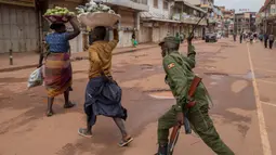 Aparat kepolisian memukul penjual jeruk saat membubarkan orang-orang yang berkeliaran di Kampala, Uganda (26/3/2020).  Pemerintah setempat juga menutup seluruh pintu perbatasan, kecuali untuk barang terbatas dan penerbangan darurat resmi sebagai upaya menekan penyebaran Covid-19. (AFP/Badru Katumba)