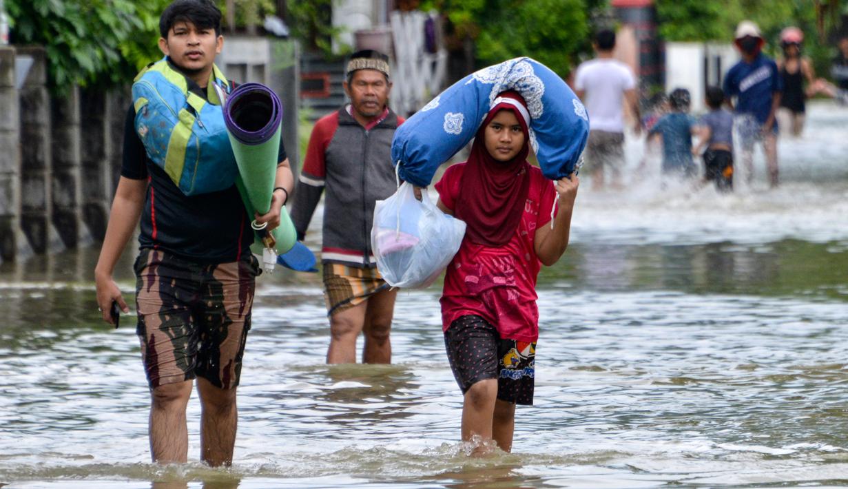 Warga melintasi lingkungan yang banjir setelah tiga hari diguyur hujan lebat di Banda Aceh, Aceh, Sabtu (9/5/2020). Banjir akibat intensitas hujan tinggi tersebut mengakibatkan sebagian besar kawasan di ibu kota Provinsi Aceh ini digenangi air. (Photo by CHAIDEER MAHYUDDIN/AFP)