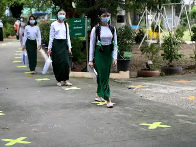 Para siswa yang mengenakan pelindung wajah dan masker berjalan dengan menjaga jarak sosial pada hari pendaftaran sekolah di Yangon, Myanmar (13/7/2020). Myanmar sejak Selasa (7/7) memulai pendaftaran sekolah untuk tahun ajaran 2020-2021, yang tertunda akibat pandemi COVID-19. (Xinhua/U Aung)