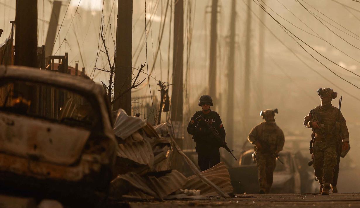 Presiden Chile, Gabriel Boric, pada Minggu 18 Januari 2026 mengizinkan pengerahan angkatan bersenjata untuk membantu upaya pemadaman. Tampak dalam foto, tentara Chile berpatroli di antara reruntuhan akibat kebakaran hutan di Concepcion, Chile pada 18 Januari 2026. (Raul BRAVO/AFP)