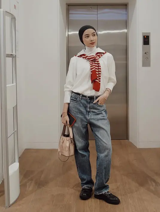 Tampil kasual dengan kerudung turban hitam, Anselma memadukannya dengan inner halter neck putih serta kemeja putih lengan panjang dan menyematkan sweater merah di pundak. Ia memilih mengenakan celana denim dan sepatu hitamnya.  [@ansellmaputri]