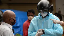 Sukarelawan petugas kesehatan dari LSM India Bharatiya Jain Sanghatana mengenakan helm pintar untuk melakukan screening kasus COVID-19 dari pintu ke pintu di Mumbai, 21 Juli 2020. Helm tersebut menjadi senjata utama bagi Mumbai dalam upaya memberantas Virus Corona. (INDRANIL MUKHERJEE/AFP)