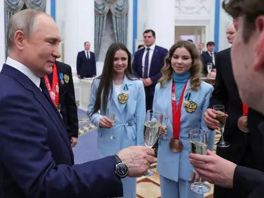 Presiden Rusia Vladimir Putin bersulang dengan atlet Rusia setelah upacara penghargaan untuk pemenang medali Olimpiade Musim Dingin Beijing 2022 di Kremlin di Moskow (26/4/2022). (Mikhail KLIMENTYEV/SPUTNIK/AFP)