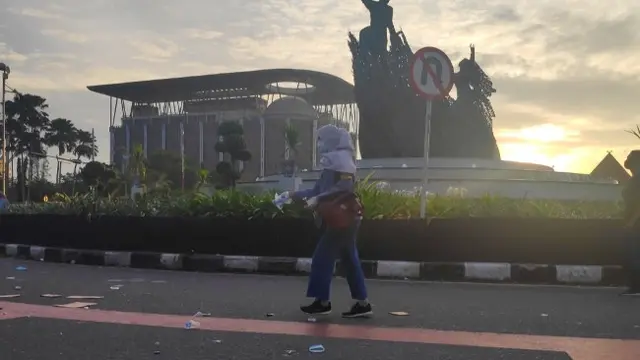 Seorang mahasiswa memungut sampah di jalan usai demo tolak Omnibus Law.