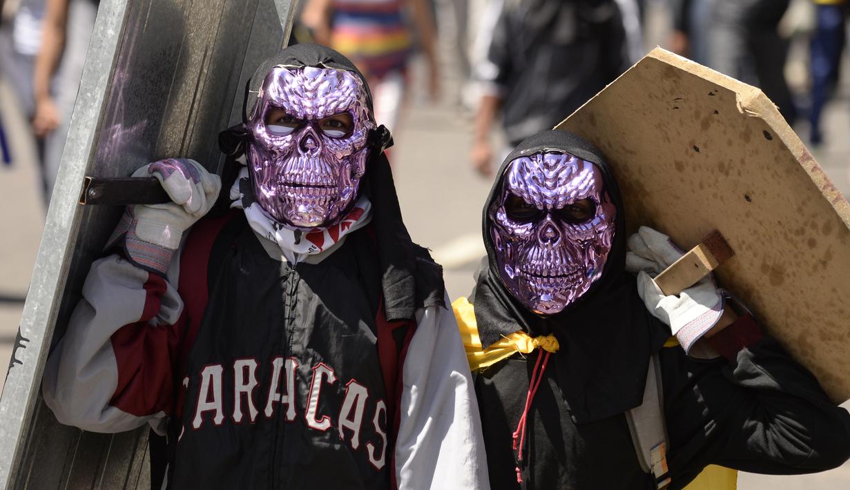 Dua demonstran menggunakan penutup wajah unik saat bentrok dengan polisi antihuru-hara menuntut Presiden Venezuela, Nicolas Maduro, di Caracas (6/7). (AP Photo / Federico Parra)