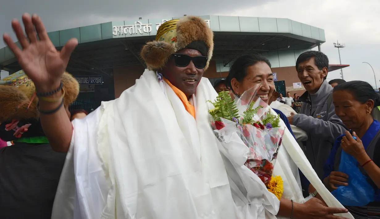 Seorang pemandu profesional, Kami Rita (48) melambaikan tangan setibanya di bandara Tribhuva,  ibu kota Nepal, Kathmandu, 20 Mei 2018. Kami Rita mencatatkan rekor dunia menjadi orang yang paling banyak mencapai puncak gunung Everest. (PRAKASH MATHEMA/AFP)