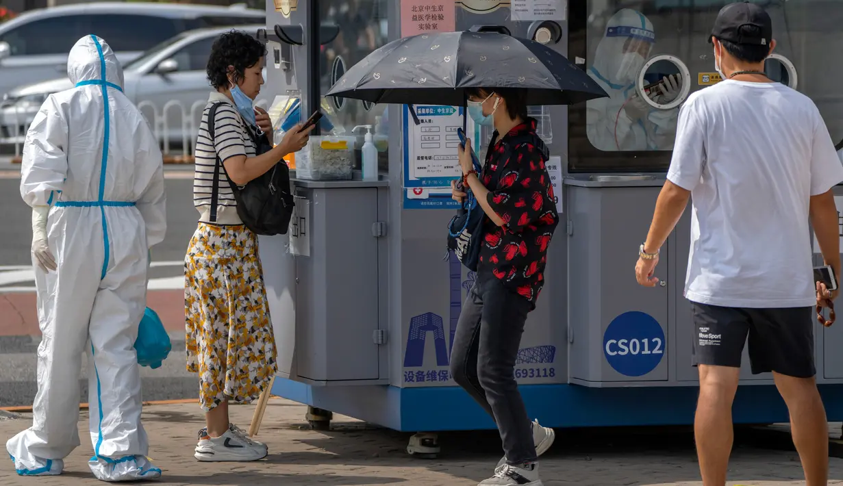 Seorang pekerja yang mengenakan pakaian pelindung menyemprotkan disinfektan ketika seorang wanita menunggu tenggorokannya diusap untuk tes COVID-19 di fasilitas pengujian virus corona di Beijing, China, Jumat (12/8/2022). REPUBLIKA.CO.ID, BEIJING -- Beberapa kota di China yang sedang dilanda wabah Covid-19 menerapkan peraturan pembatasan sosial baru. (AP Photo/Mark Schiefelbein)