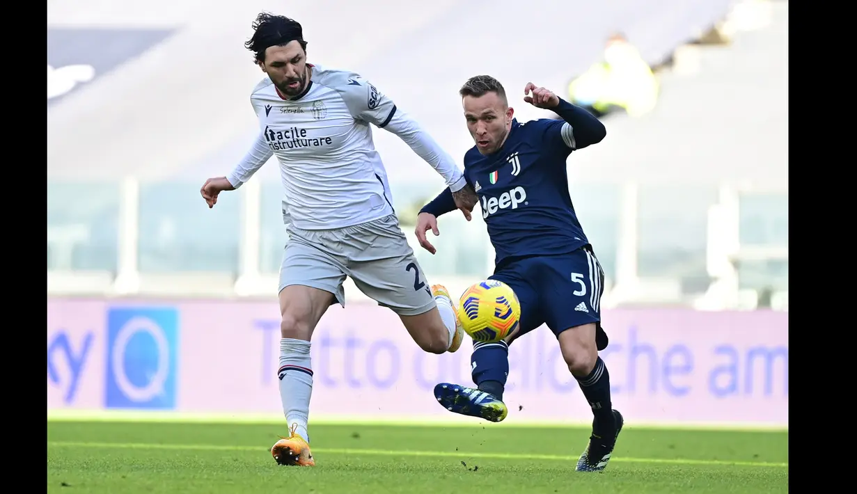 Pemain Juventus, Arthur (kanan) berusaha melewati hadangan pemain Bologna dalam laga lanjutan Liga Italia di Stadion Allianz, Turin, Minggu (24/1/2021). (Foto: AFP/Miguel Medina)