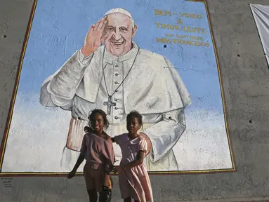 Anak-anak perempuan berdiri di depan foto dinding menyambut Paus Fransiskus di Dili, Timor Leste, Selasa, 3 September 2024. (AP Photo/Firdia Lisnawati)