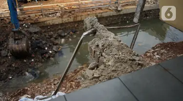 Alat berat mengeruk beton turap saluran air yang longsor di kawasan Jagakarsa, Jakarta, Kamis (17/9/2020). Selain karena hujan lebat, longsor diduga karena erosi tanah akibat pembuangan saluran air pencuci piring dan toilet dari warung makan di sekitar bantaran. (Liputan6.com/Immanuel Antonius)