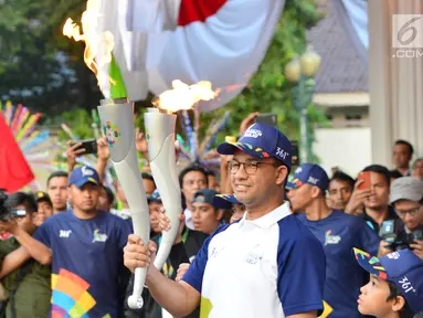 Gubernur DKI Jakarta, Anies Baswedan membawa Api Obor Asian Games 2018 setelah mengelilingi dari Jakarta Timur dan Jakarta Selatan di Balai Kota, Jakarta, Rabu (15/8). (Liputan6.com/Fery Pradolo)