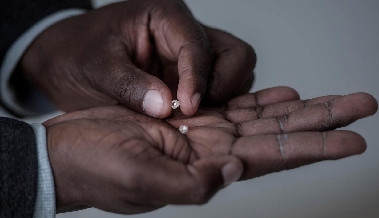 Seorang pria memegang berlian kasar yang ditemukan Clara Maitse di bekas pertambangan ilegal di Kimberley, Northern Cape, Afrika Selatan (5/6). (AFP/Mujahid Safodien)