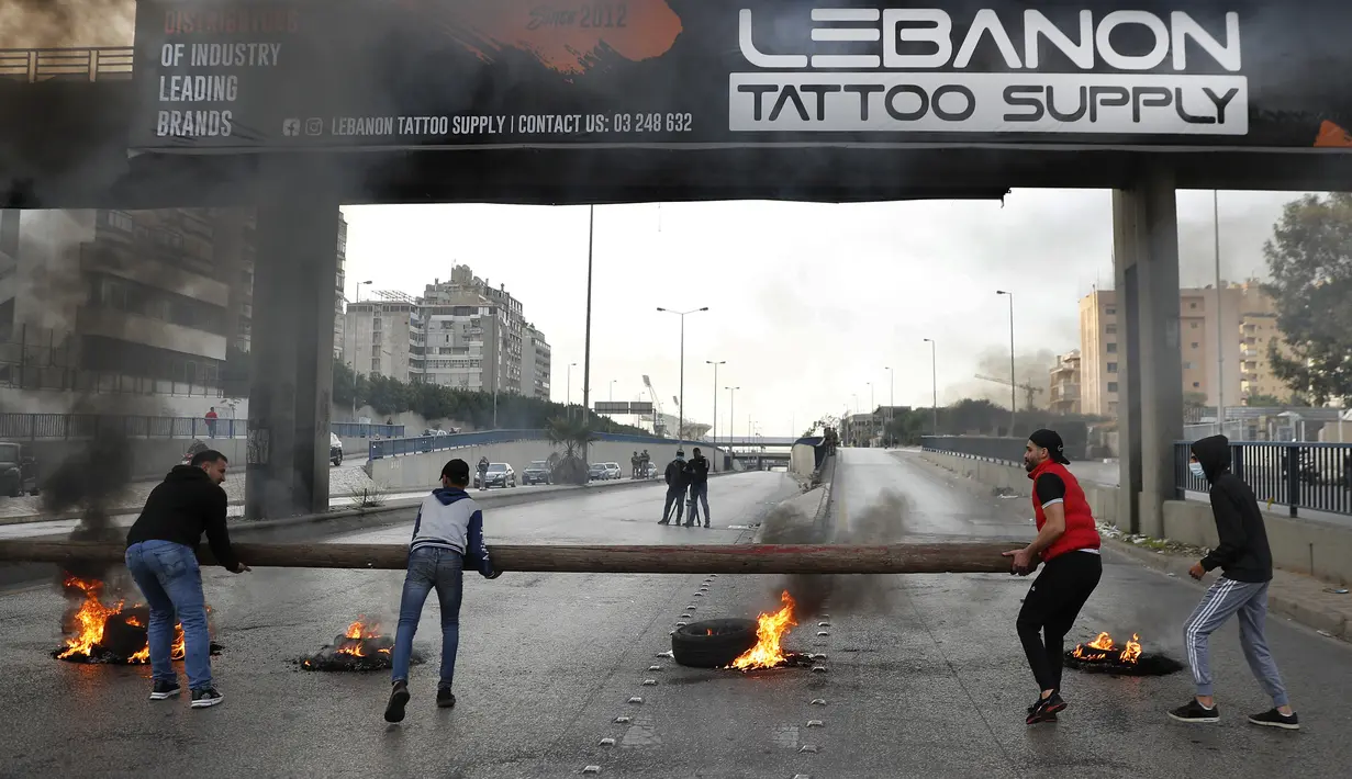 Para pengunjuk rasa memblokir jalan raya utama yang mengarah ke Bandara Internasional Beirut selama protes terhadap kenaikan harga barang-barang konsumsi dan jatuhnya mata uang lokal di Beirut, Lebanon, Senin (29/11/2021). (AP Photo/Hussein Malla)