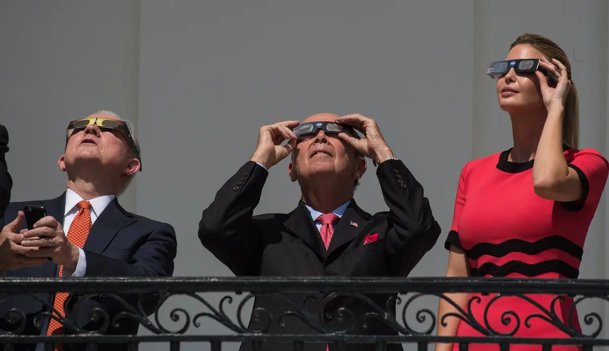 Putri Presiden AS Donald Trump, Ivanka Trump bersama Sekretaris Perdagangan AS Wilbur Ross (tengah) dan Jaksa Agung Jeff Sessions menyaksikan fenomena langka gerhana matahari total dari balkon Gedung Putih di Washington, Senin (21/8). (NICHOLAS KAMM/AFP)