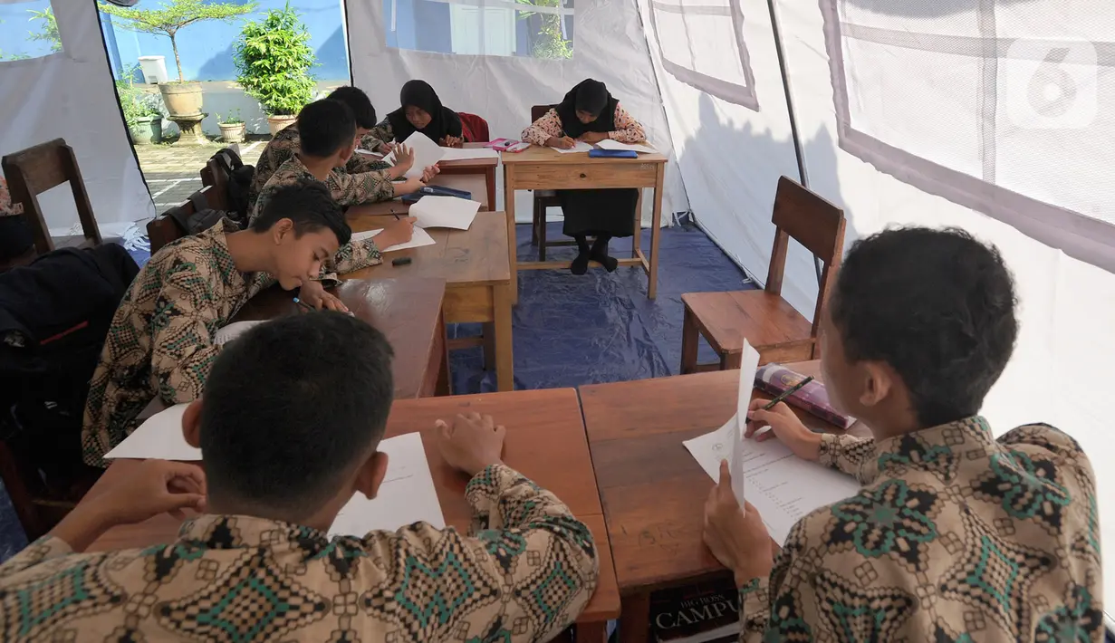 Murid SMP dan SMA Sekolah Khusus Assalam 01 melaksanakan ujian di tenda darurat halaman SKh Assalam 02, Ciater, Serpong, Tangerang Selatan, Selasa (3/12/2019). Sebanyak 84 murid penyandang tunarungu, tunawicara, dan tunagrahita terpaksa mengikuti ujian di tenda darutat. (merdeka.com/Arie Basuki)