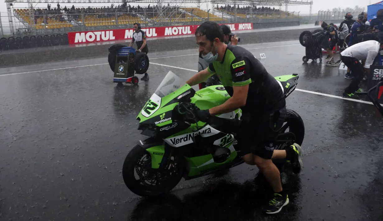 Seorang mekanik mendorong motor ke paddock saat hujan deras sebelum Race 1 World Superbike (WSBK) di Pertamina Mandalika International Street Circuit, Lombok Tengah, Nusa Tenggara Barat, Sabtu (20/11/2021). Hujan deras memaksa Race 1 WSBK Mandalika ditunda pada 21 November. (AP Photo/Achmad Ibrahim)