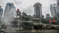 Para pekerja membersihkan patung kuda Arjuna Wijaya di Jalan Medan Merdeka, Jakarta, Rabu (27/1/2021). Patung yang dibangun sejak 1987 karya pematung Nyoman Nuarta tersebut dibersihkan dan ditata kembali untuk memperindah kota. (Liputan6.com/Faizal Fanani)