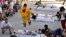Pria berkostum setan melompati bayi-bayi yang terlentang di atas matras di sebuah jalan selama festival El Colacho di desa Castrillo de Murcia, Spanyol, Minggu (18/6). Tindakan ini bermakna untuk membersihkan bayi dari roh-roh jahat. (CESAR MANSO/AFP)