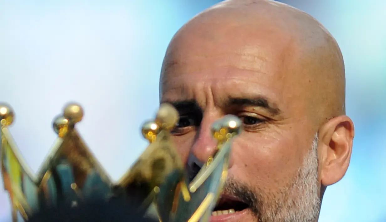 Manajer Manchester City Pep Guardiola melihat trofi Liga Primer Inggris usai pertandingan melawan Huddesfiel di Etihad Stadium (6/5). Manchester City resmi mendapatkan trofi juara Liga Inggris atau Premier League 2017-2018. (AP Photo / Rui Vieira)