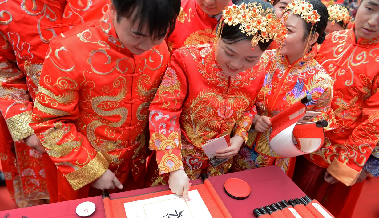 Mempelai membubuhkan sidik jari pada tulisan kaligrafi tradisional dalam pernikahan massal bergaya China di Changsha, Provinsi Hunan, China, 25 September 2020. Sebanyak 71 pasangan resmi menjadi suami-istri usai mengikuti upacara pernikahan tradisional dalam acara nikah massal. (Xinhua/Chen Zhenhai)