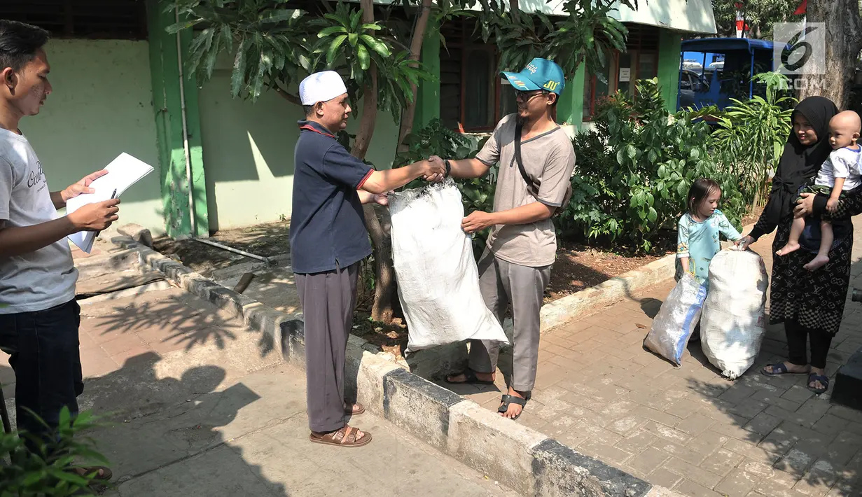 Ketua Bank Sampah Majelis Taklim Solihin (berpeci) saat menerima karung sampah dari salah satu nasabah di Kecamatan Koja, Jakarta, Senin (15/7/2019). Bank Sampah Majelis Taklim membanderol harga sampah Rp3.000-4.000 per kilogram. (merdeka.com/Iqbal S. Nugroho)