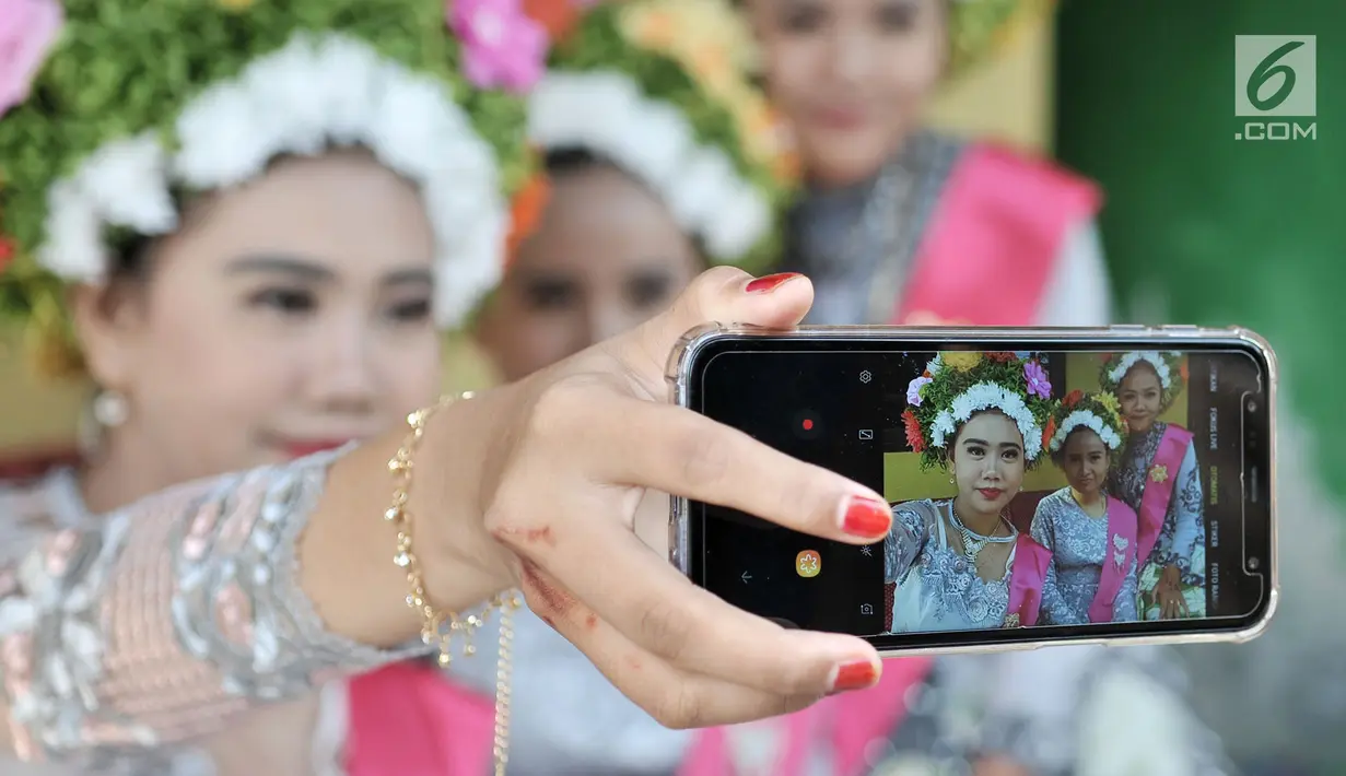 Sejumlah gadis berswafoto saat menunggu upacara adat Ngarot dimulai di Desa Lelea, Indramayu, Jawa Barat, Rabu (19/12). Hari Rabu minggu ketiga di bulan Desember dipercaya oleh masyarakat setempat sebagai hari keramat. (Merdeka.com/Iqbal Nugroho)