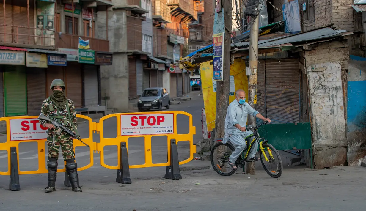 Pria Kashmir melintasi barikade yang digunakan untuk memblokir jalan di Srinagar, Kashmir yang dikuasai India, Rabu (5/8/2020). Tentara India memperketat keamanan di Kashmir dalam upaya menahan serangan dalam peringatan setahun pelepasan status otonomi khusus wilayah tersebut. (AP Photo/ Dar Yasin)