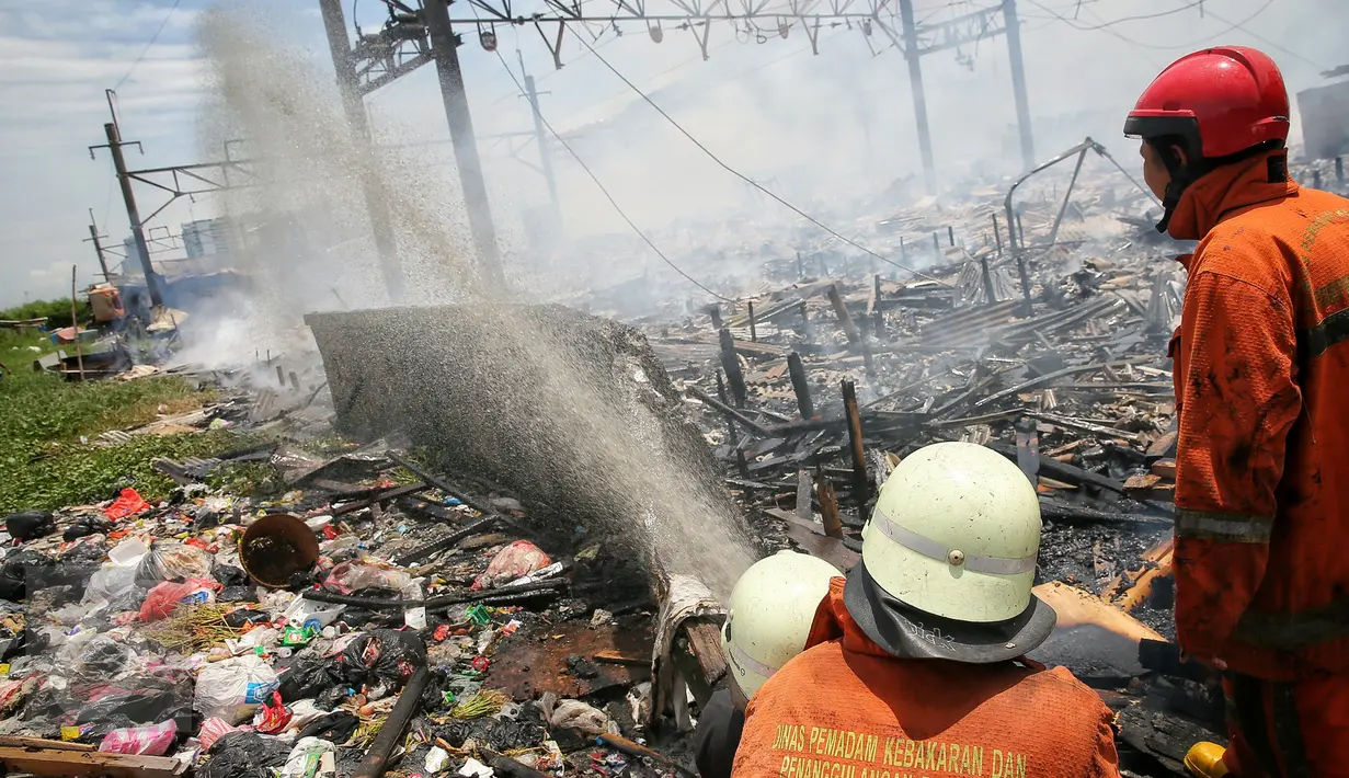 Petugas pemadam berusaha memadamkan api yang membakar ratusan rumah di Kampung Bandan, Ancol, Jakarta, Selasa (26/1). Kebakaran tersebut juga berdampak pada perjalanan KRL lintas Jakarta Kota-Manggarai. (Liputan6.com/Faizal Fanani)