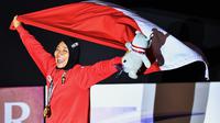 Peraih medali emas Indonesia Susanti Rahayu Aries membawa bendera merah putih pada upacara penyerahan medali olahraga panjat tebing wanita Asian Games 2018 di Palembang (23/8). (AFP PHOTO / Adek Berry)