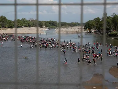 Migran Amerika Tengah menyeberangi Sungai Suchiate dengan berjalan kaki dari Guatemala ke Meksiko, Tecun Uman, Guatemala, Senin (20/1/2020). Lebih dari seribu migran Amerika Tengah yang terdampar di Guatemala berjalan massal untuk menuju Amerika Serikat. (AP Photo/Moises Castillo)