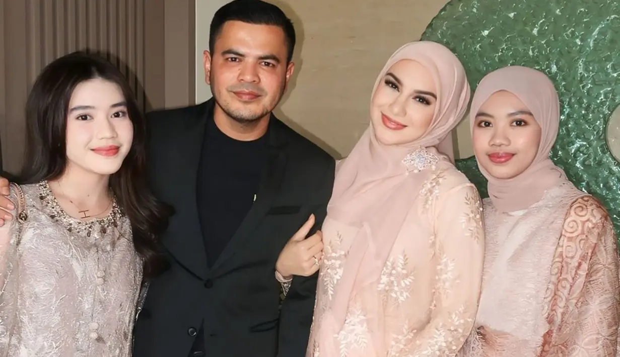 Irish Bella untuk pertama kalinya membagikan momen kondangan bersama keluarga barunya. Dengan senyum semringah, Irish tampak menggandeng suaminya yang berpenampilan rapi mengenakan setelan jas hitam. Sementara, penampilannya tampak senada dengan dua anak sambungnya. (Liputan6.com/IG/@_irishbella_)