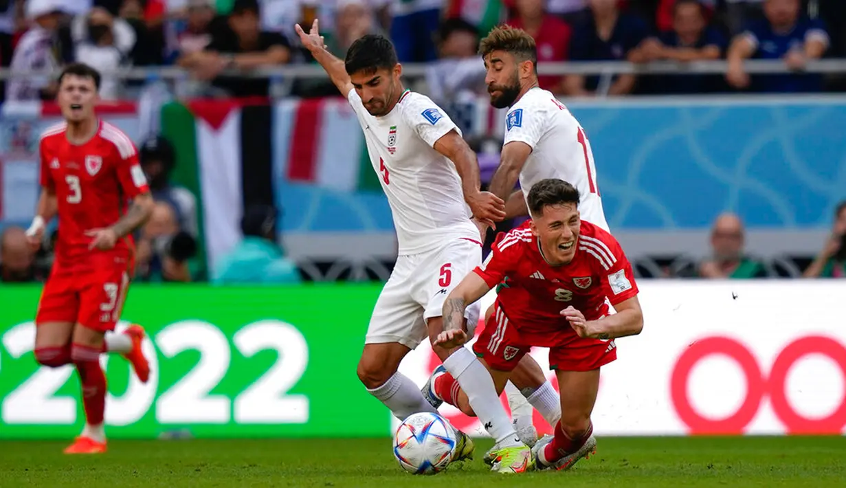 Pemain Iran Milad Mohammadi (kiri) berebut bola dengan pemain Wales Harry Wilson pada pertandingan sepak bola Grup B Piala Dunia 2022 di Stadion Ahmad Bin Ali, Al Rayyan, Qatar, Jumat (25/11/2022). Iran mengalahkan Wales dengan skor 2-0. (AP Photo/Frank Augstein)