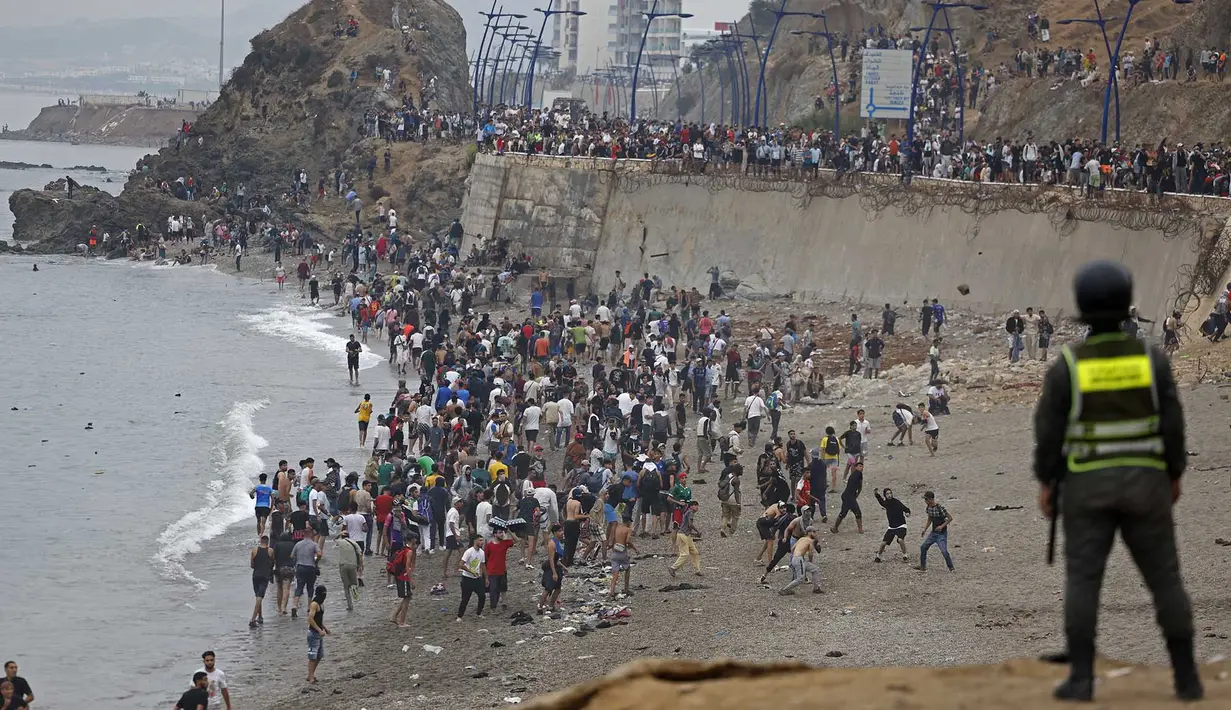 Para imigran berkumpul di sepanjang pagar di lokasi bentrokan dekat Fnideq, di perbatasan Maroko-Spanyol, Jumat, 31 Juli 2026. (AFP/  Abdel Majid Bziouat)