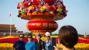 Para wisatawan berfoto di depan "keranjang bunga" di Lapangan Tian'anmen di Beijing, ibu kota China (24/9/2020). Dekorasi setinggi 18 meter berbentuk keranjang bunga itu ditempatkan di tengah Lapangan Tian'anmen untuk menyambut masa libur Hari Nasional China mendatang. (Xinhua/Chen Zhonghao)